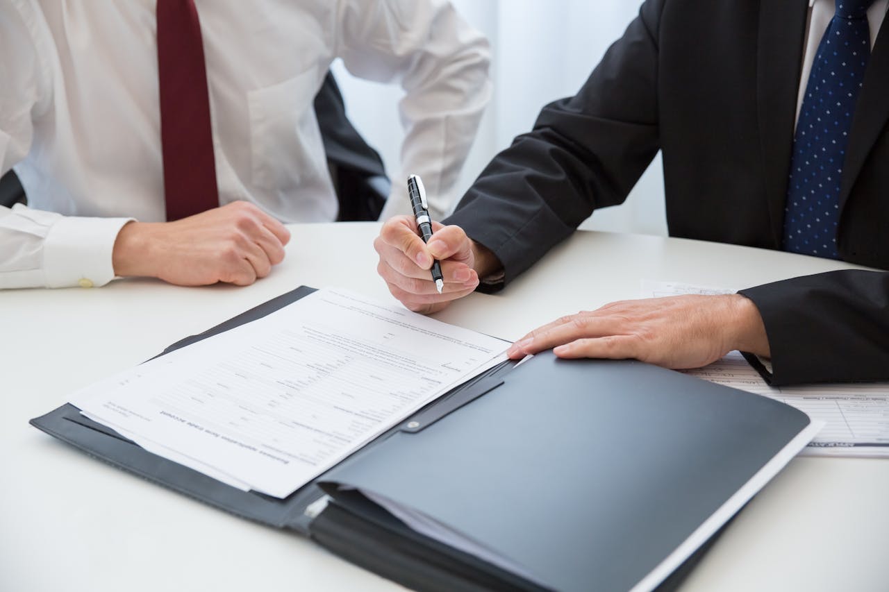 why-choose-us Two professionals signing a contract at a business meeting in an office.